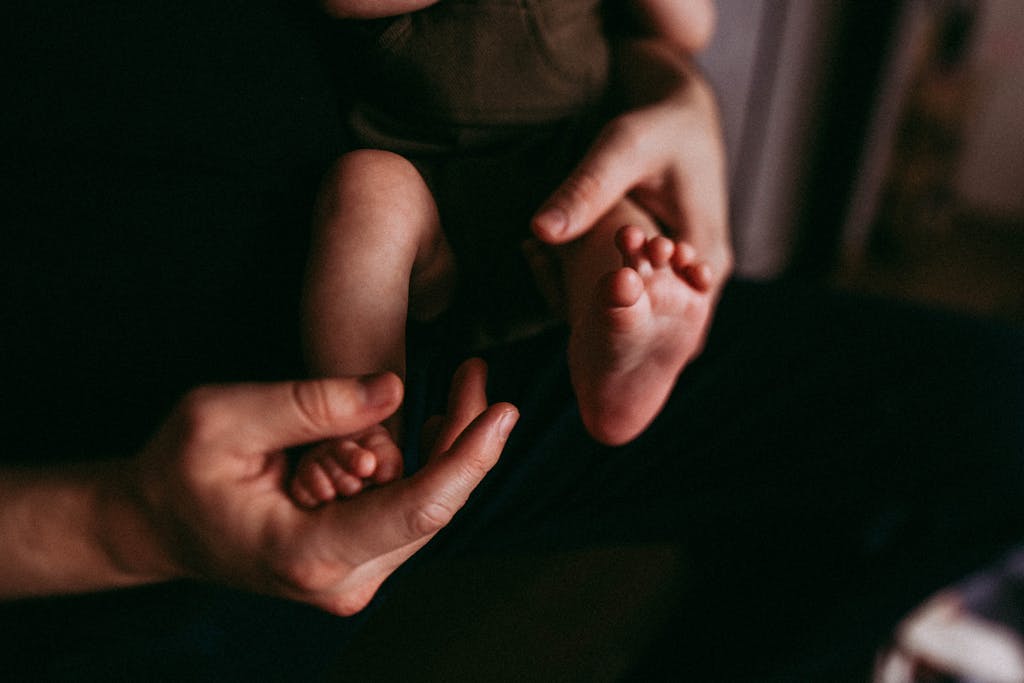 Crop parent touching feet of baby in flat